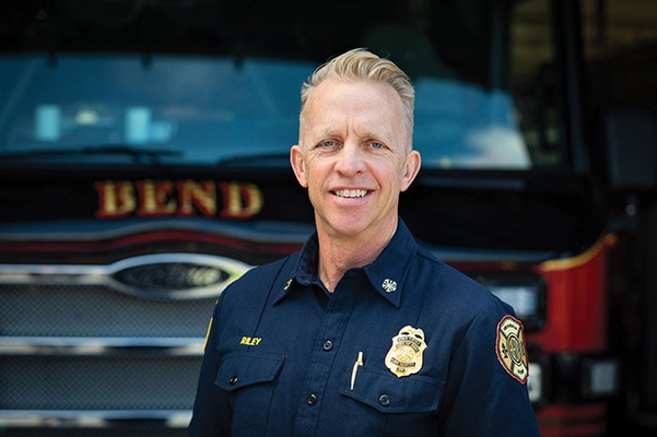 Bend Fire and Rescue Fire Chief posed in front of Pierce fire truck.