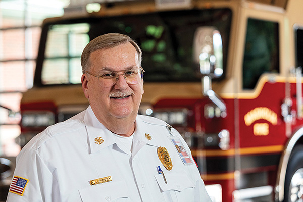 Fire Chief standing in front of fire truck parked in fire station