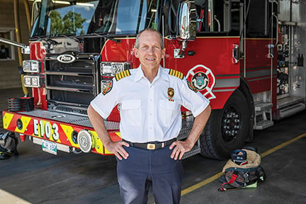 Winnipeg Fire Chief standing in front of his new Pierce pumper fire truck with the drivers side door open