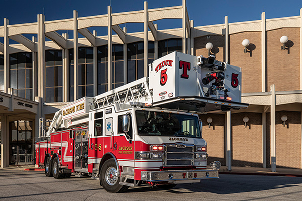 Aerial platform fire trick parked in front of building outside during the day time