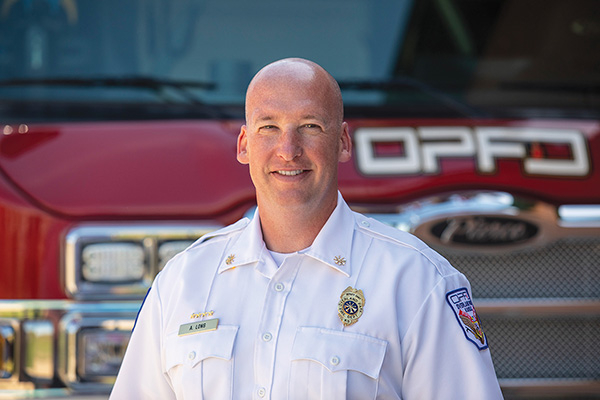 Overland Park Fire Chief smiling in front of a Pierce aerial ladder fire truck