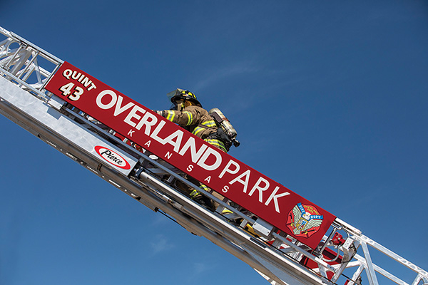 Firefighter climbing up 75' ladder fire truck