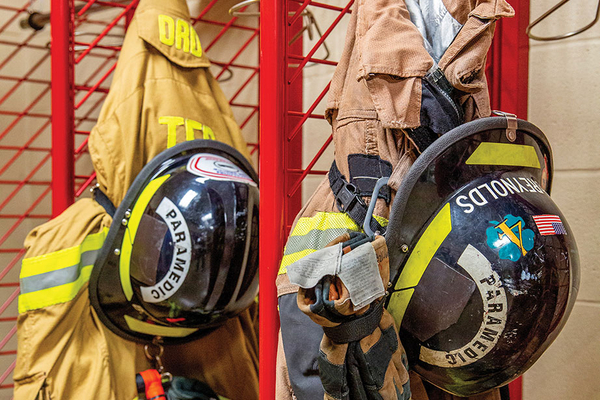 Firefighter helmets and bunker gear hanging in locker of fire house