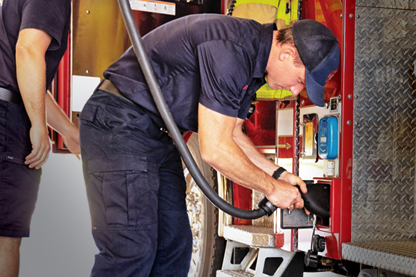 Firefighter plugging in electric fire apparatus in fire station utilizing the electrical fire truck charging infrastructure. 