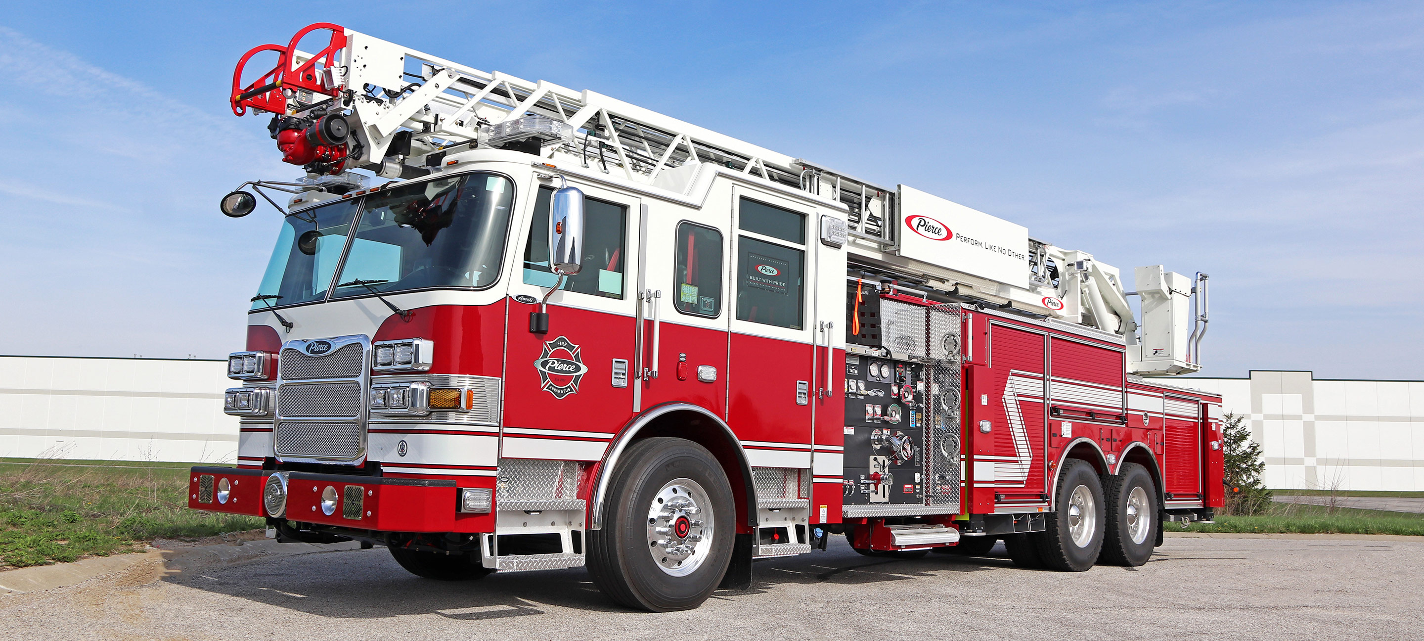 A side view of a red and white 100' Heavy-Duty Low Profile Steel Aerial Ladder truck.