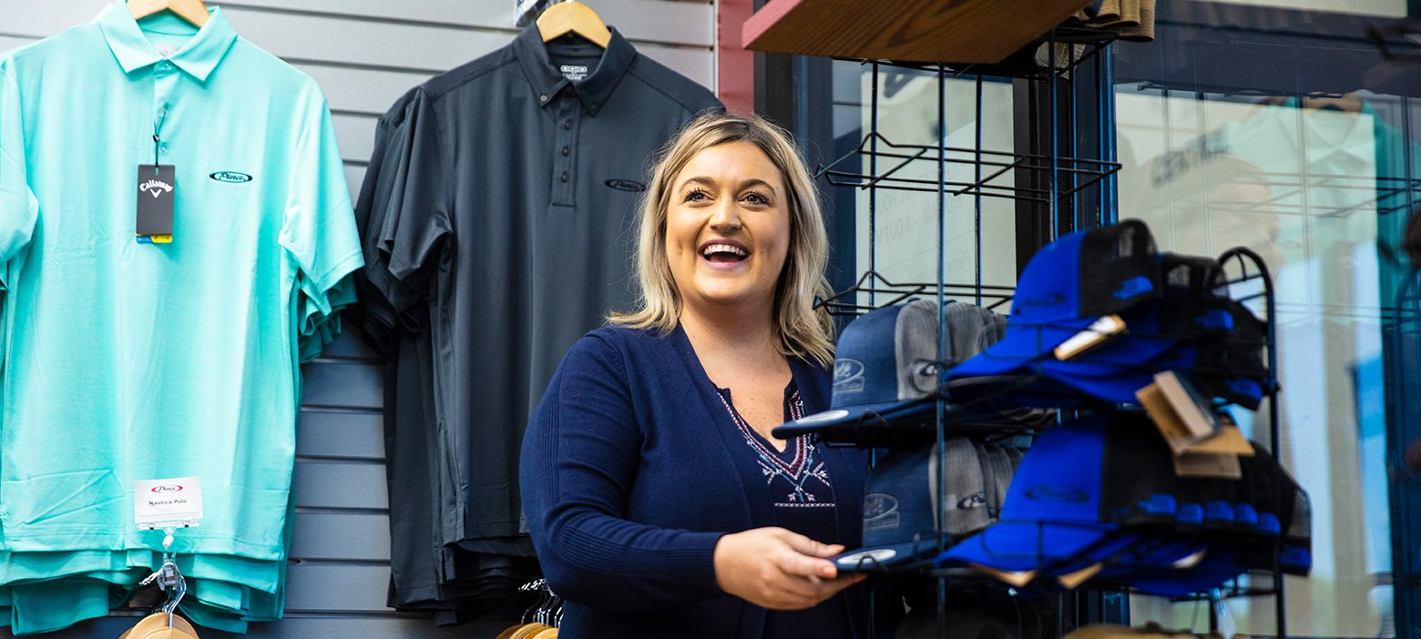 Female employee smiling and laughing while restocking Pierce branded merchandise in company store